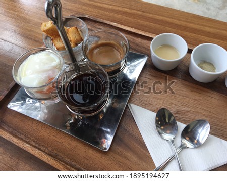 a selective focus photo of a set of breakfast which are black coffee, tea, soft-boiled eggs and baked bread.