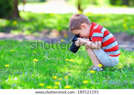 cute kid boy photographing flowers