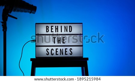 Cinema Light box. Behind the scenes letterboard text on Lightbox. Multi color LED on background. Sillhouette flash snoot hood on tripod. video production studio. Behind the scene Lightbox