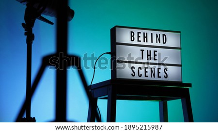 Cinema Light box. Behind the scenes letterboard text on Lightbox. Multi color LED on background. Sillhouette flash snoot hood on tripod. video production studio. Behind the scene Lightbox