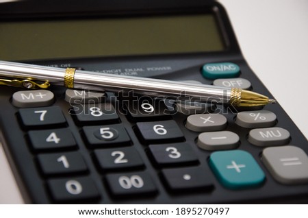 calculator and pen lie on a white background. High quality photo