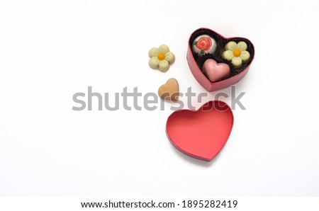 A small box in the shape of a heart with chocolates as a gift for a loved one for Valentine's Day, isolated on a white background.