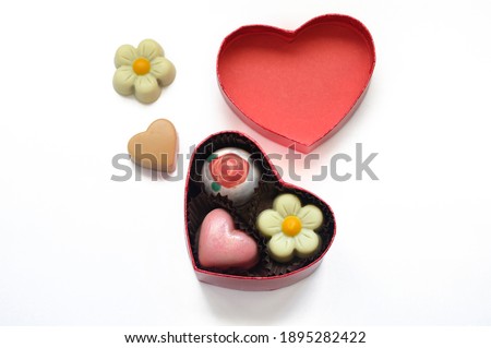 A small box in the shape of a heart with chocolates as a gift for a loved one for Valentine's Day, isolated on a white background.