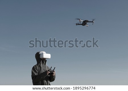 Tourist exploring new places. Drone pilot on nature with quadcopter. Using drone while standing near lake. Young person  with drone and virtual reality viewer. Royalty-Free Stock Photo #1895296774
