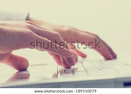 Close up faded effect retro style image of the hands of a man typing on a laptop keyboard. Royalty-Free Stock Photo #189550079