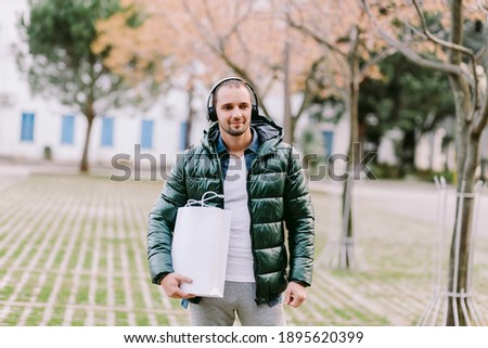 man holding White paper bag and white t-shirt mockup. Blank label bag for print and t-shirt mockup. outdoors single object.