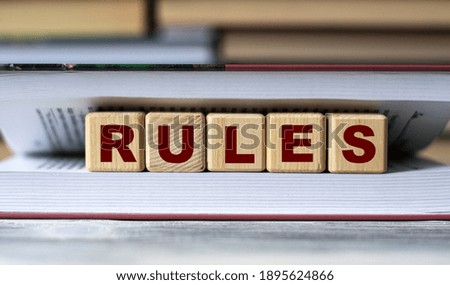 RULES - word on wooden cubes against the background of the open book. Info concept