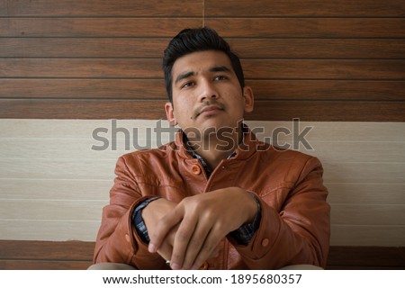 picture of boy wearing brown leather coat, thinking about something.
