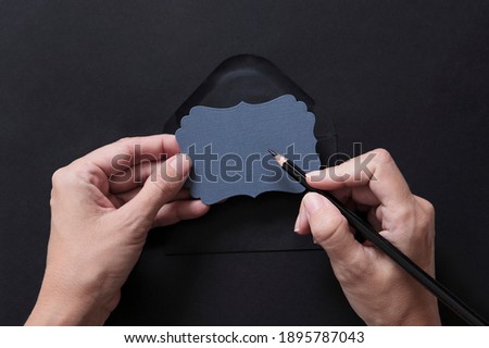 Woman's hands writing a message in a note on black background. Copy Space.