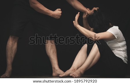 Violent male threatening his wife with his fist in dark background
