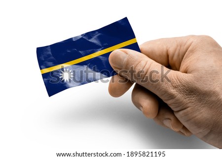Hand holding a card with a national flag the Nauru