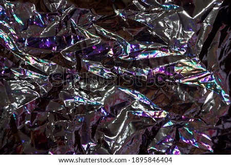 Abstract photo, violet vibrant futuristic lively color lighting reflected on aluminium foil snack package close up shot in Thailand for background usage.