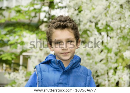 Curly boy standing outside in the spring.