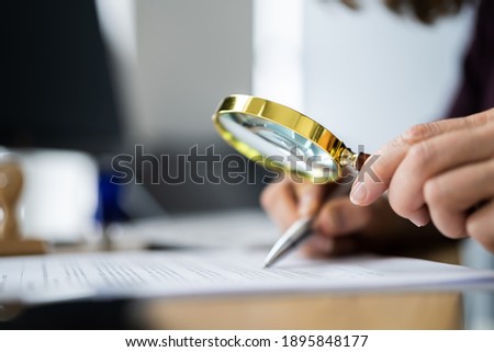 Auditor Doing Tax Fraud Investigation Using Magnifying Glass Royalty-Free Stock Photo #1895848177