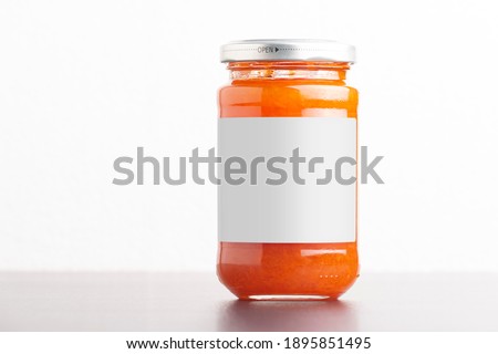 Juicy homemade carrot jam in glass jars on a white background, editable mock-up series template ready for your design, label selection path included.