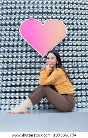 Asian beautiful woman with long hair is sitting and smiling in heart background as Valentine’s  day concept.