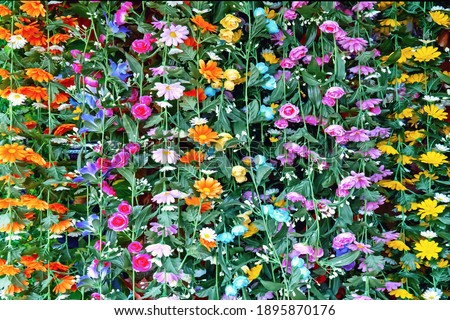 Background from artificial multi-colored flowers forming vines