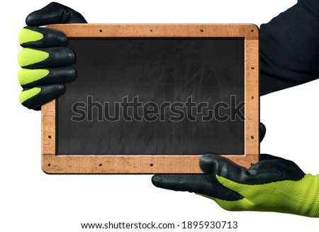 Hands with protective work gloves hold a blank blackboard with wooden frame, isolated on white background with copy space.