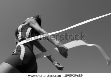 Black and white photo of female athlete crossing finish line(Motion blurr) Royalty-Free Stock Photo #1895939689