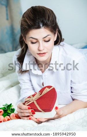 Beautiful girl open red heart gift box. Valentine's day. Happy Birthday.  Girl receives a gift at home.
