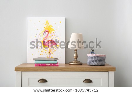 Stationery, picture and toy on wooden chest of drawers in children's room. Interior design