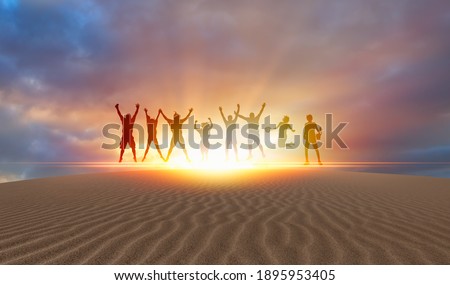 Silhouette of friends jumping on the sand dune of desert at Sunset 