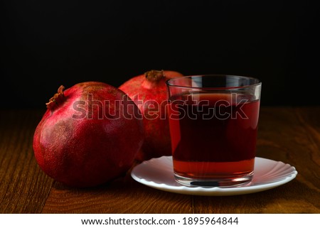 Fruits of a juicy ripe pomegranate and a glass of pomegranate juice on a dark background. Shallow depth of field.