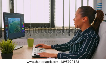 Freelancer hispanic videographer editing new project working in modern company creating content. Entrepreneur in professional workspace writing on computer keyboard looking at desktop