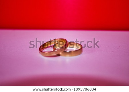 gold wedding rings for valentines day on a red and white background