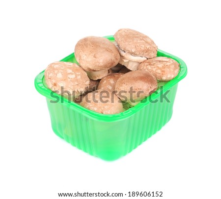 Green plastic box full of champignons. Isolated on a white background.