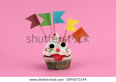 cupcake with funny crazy face on pink background isolated