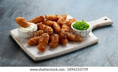 Battered Haddock fish, mini fingers with mashed peas, tartar sauce on white wooden board