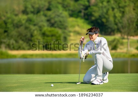 Asian man golfer  sitting  on fairway aiming ball to  golf hold at golf course  , Sport healthy holiday lifestyle  Concept , Banner for text