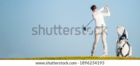 Asian man golfer standing  on slope  with golf bag hitting  golf ball on blue sky background  at golf course , Sport healthy holiday lifestyle  Concept , Banner for text