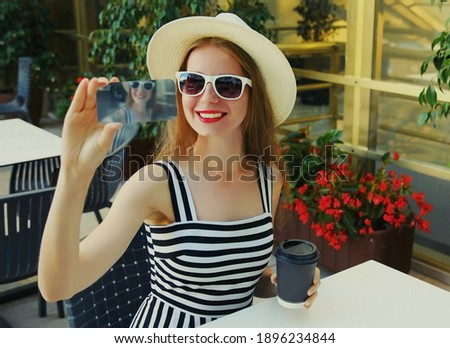 Portrait of happy smiling young woman taking selfie picture by smartphone sitting at a table in a cafe