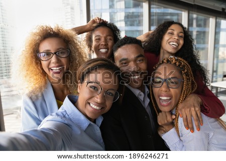 Close up portrait of overjoyed young multiracial employees team have fun posing for selfie on smartphone in office together. Happy smiling diverse multiethnic colleagues male self-portrait picture.