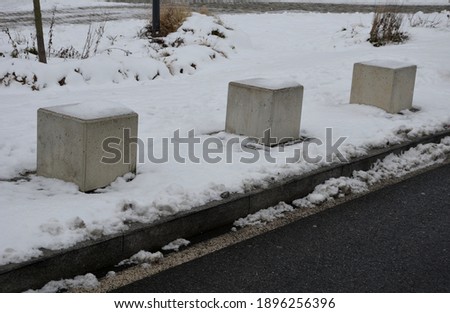 barrier along the road with concrete, cement cubes. It is snowing and frosty in winter. It acts as a pedestrian protection and navigation equipment for urban space