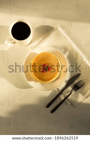 Pancakes on a white plate with raspberries and mint. Light background