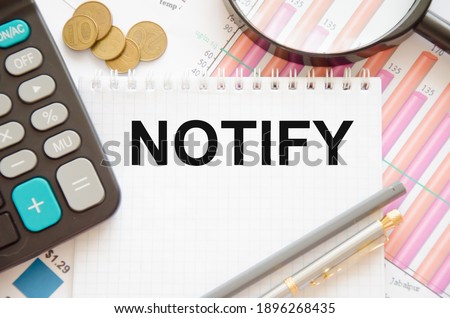 the word notify is written on a white notebook with a calculator and a magnifying glass, a pen and coins that puddle on a financial chart. High quality photo