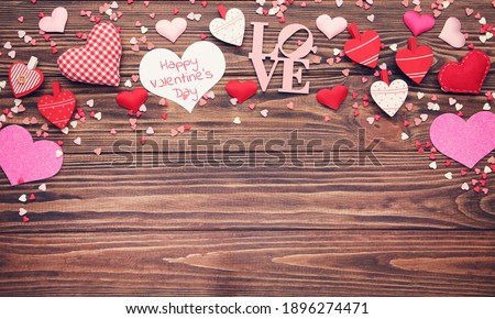 Text Happy Valentines Day with hearts and sprinkles on brown wooden background