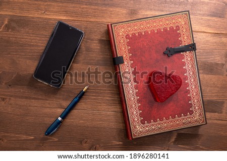 notebook and red heart and pen on dark table