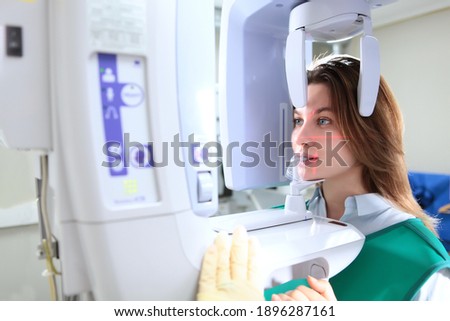 Panoramic image of the jaw in the dental laboratory. Modern medicine. The girl takes a picture of her teeth. Prevention and treatment of teeth. Vertical photo.X-ray equipment. Side view.