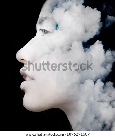 A portrait of a young  hispanic woman's profile against dark background combined with a photo of clouds in a double exposure technique