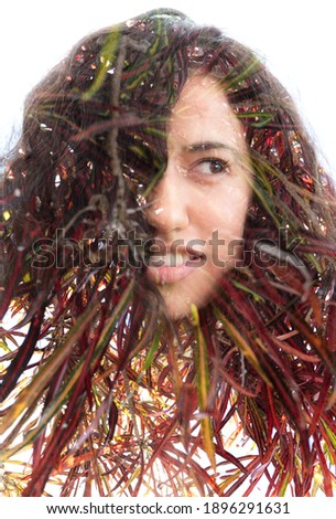 A portrait of a young woman with curly hair half smiling and looking away from the camera combined with a photo of a colorful exotic plant in a double exposure technique against white background 