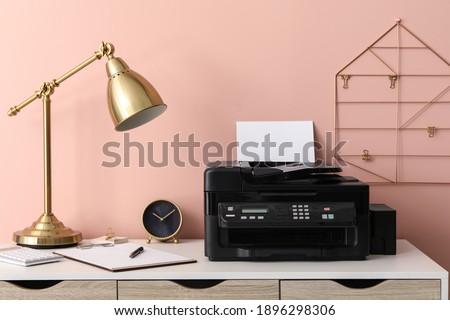 New modern printer with paper on white table at workplace