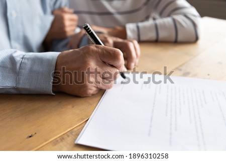 Close up elderly senior family couple signing contract with real estate agent purchasing accommodation, making agreement with financial advisor or putting signature on paper medical insurance.