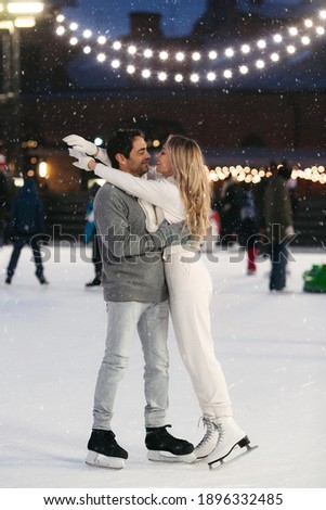 Happy couple of lovers having fun, hugging at ice skating rink outdoor. St. Valentines Day, Winter leisure, New Year holidays concept.