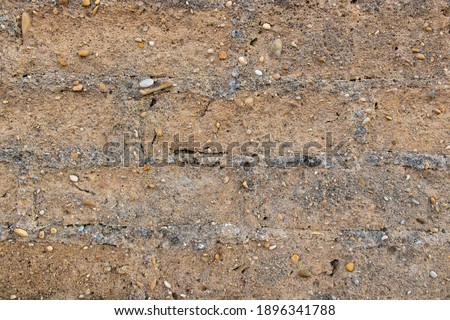 Clay wall background. Detail of old wall made of clay with roughly built bricks and mixed pebbles. Texture of rough rustic wall with copy space. Materials and construction industry concept