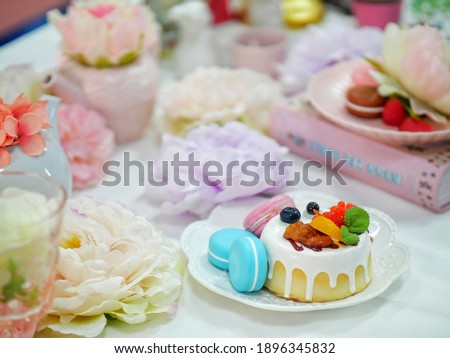 Cake with macaron on the table brings tea filled with flowers.
