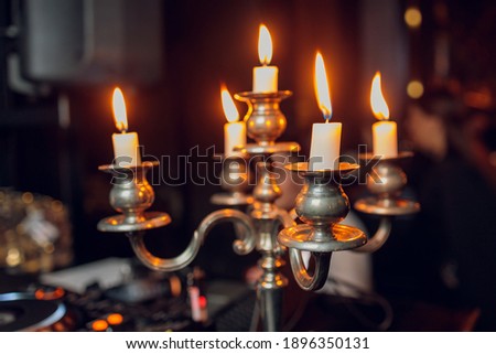 Metal retro candlestick with five burning candles against a dark background in the room home, selective focus.